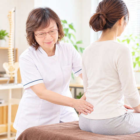 腰痛に悩み腰を押さえる女性のイメージ
